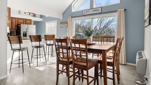 A modern kitchen with wooden cabinets, a dining area with a large table and chairs, and a window with a view of trees. - Lakefront home in Osage Beach - Newly Renovated (Osage Beach)
