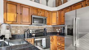 A kitchen with wooden cabinets, stainless steel appliances, granite countertops, and a tiled backsplash. - Lakefront home in Osage Beach - Newly Renovated (Osage Beach)