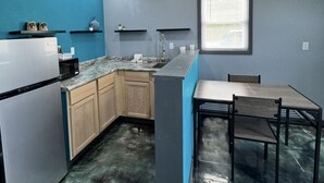 Cocina compacta con refrigerador, microondas y gabinetes de madera.
