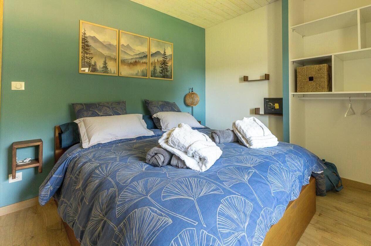 A bedroom with a bed, a nightstand, a wall-mounted lamp, and a shelf with storage boxes.