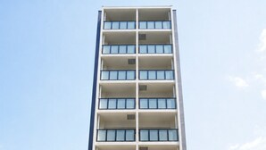 A multi-story building with a modern design, featuring balconies on each floor, a brick base, and a sign indicating a global presence. - reside global kumamoto (Kumamoto)