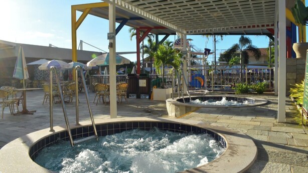 A hot tub area with a covered seating area, outdoor tables, and chairs. - IL Locações di Roma Fiori (Caldas Novas)