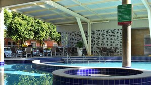 A swimming pool with blue tiles, a covered area with chairs, and a sign indicating adult supervision. - IL Locações di Roma Fiori (Caldas Novas)