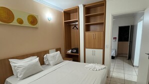 A hotel room with a bed, a wardrobe, a small table, and a wall-mounted artwork. - IL Locações di Roma Fiori (Caldas Novas)
