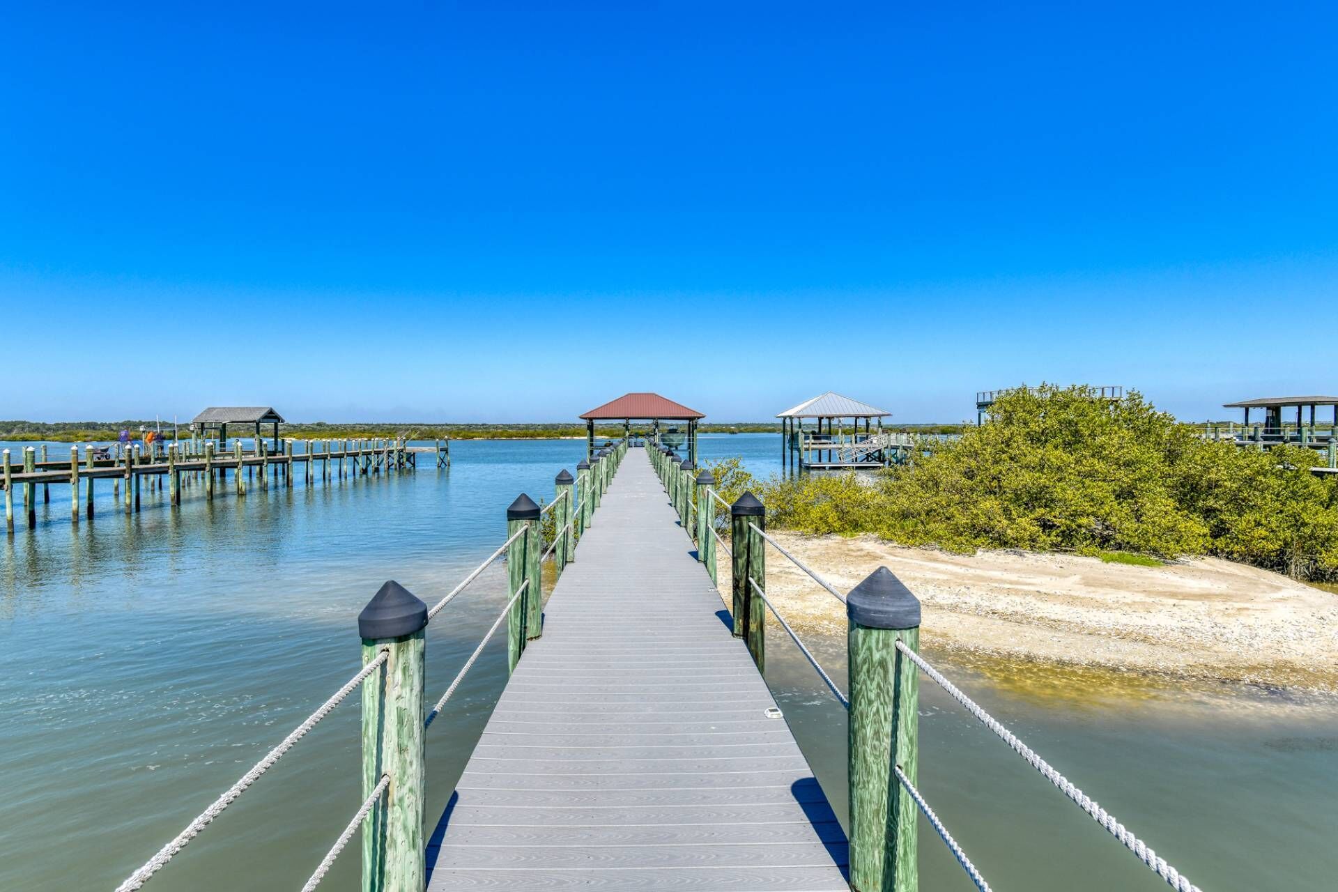 A wooden pier extending into calm water, with a clear sky above.