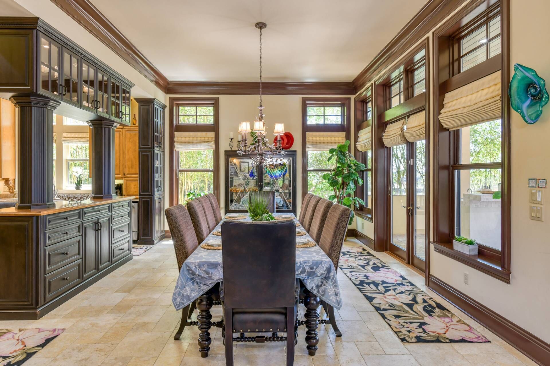 A dining area with a long table, chairs, and a chandelier.