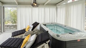 Ein Wellnessbereich mit Whirlpool, zwei Liegestühlen und einer Deckenleuchte.