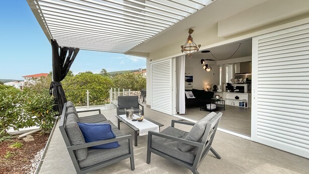 Eine moderne Außenpatio mit einer Couch, Stühlen und einem Tisch.