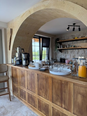 Een keuken met een houten bar, koffieapparaten en diverse keukengerei.