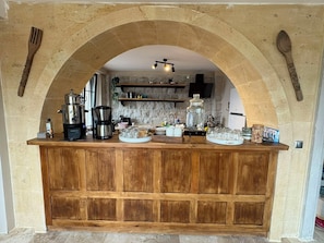 Una cocina rústica con mostrador de madera, cafeteras y frascos de vidrio.