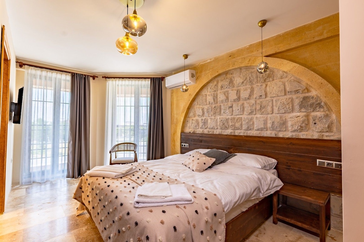 Un dormitorio con arco de pared de piedra, estructura de cama de madera y lámpara colgante.