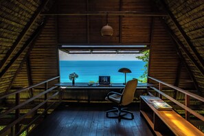 Ein Zimmer mit Meerblick, ein Schreibtisch mit Stuhl, eine Lampe und eine Bank.