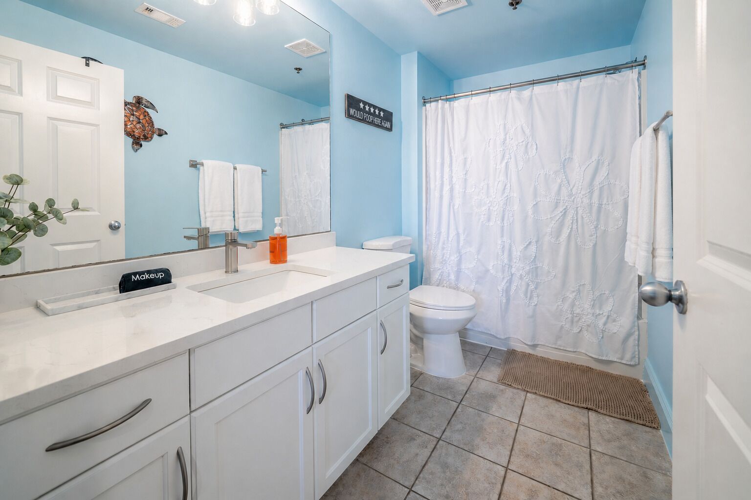 Een badkamer met een wit wastafel, toilet en douchegordijn.