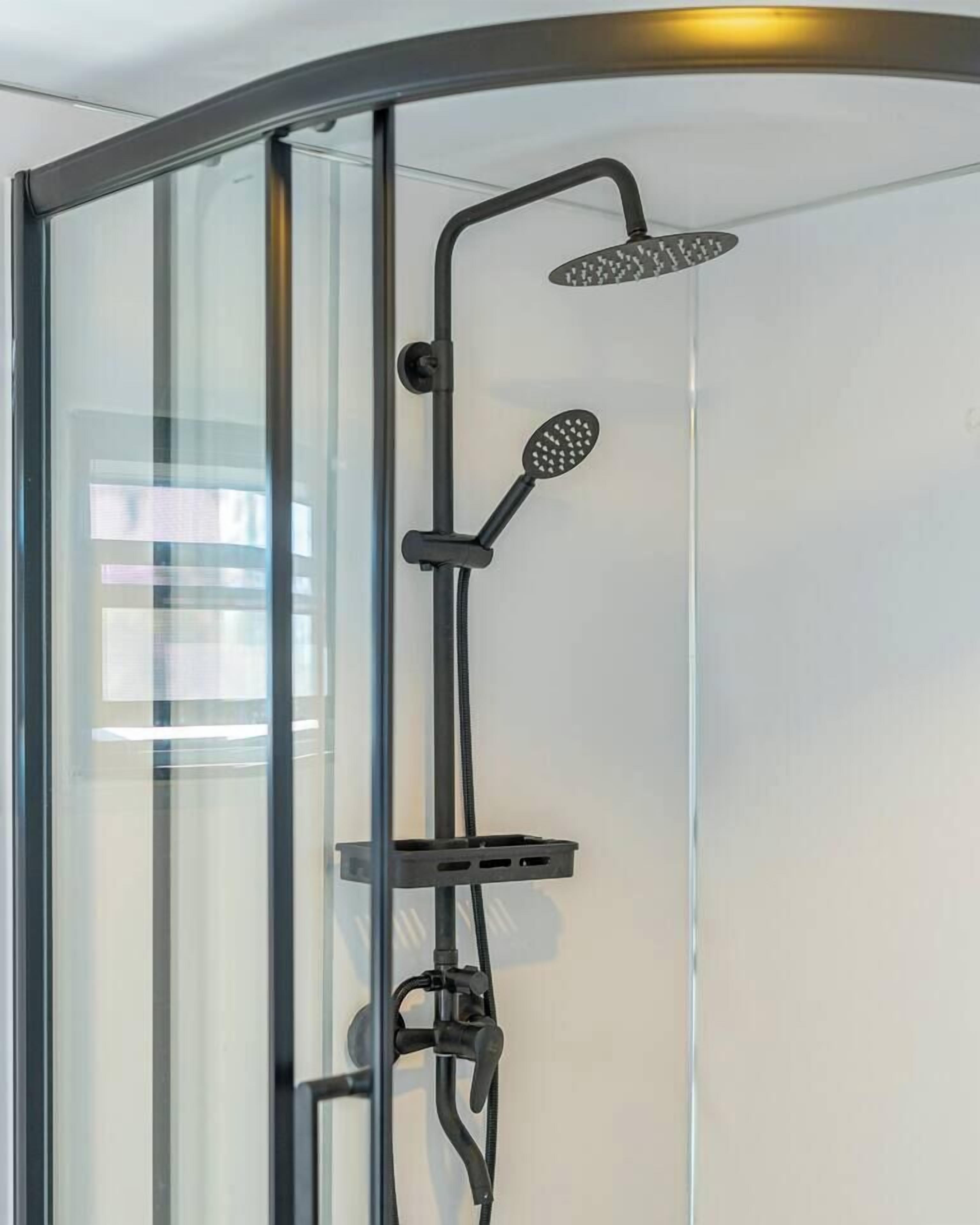 A modern shower enclosure with a glass door, a handheld showerhead, and a rain shower attachment.