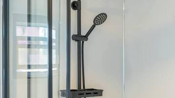 A modern shower enclosure with a glass door, a handheld showerhead, and a rain shower attachment.