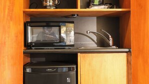 Cocina compacta equipada con microondas, cafetera y refrigerador pequeño.