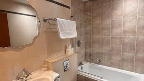 A bathroom with a sink, toilet, bathtub, and a mirror. - The Strand Hotel (Blackpool)