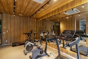 Academia com máquinas de cardio, espelho, paredes de madeira e iluminação no teto.