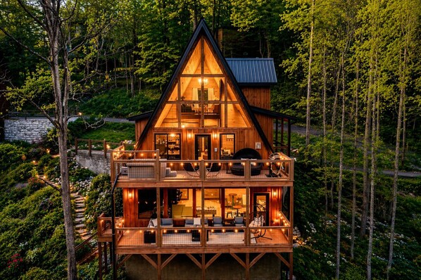 Eine zweistöckige Blockhütte mit Balkon, umgeben von Wald.