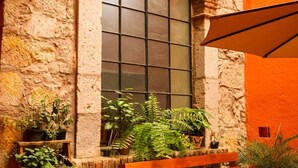 A stone wall with a window, wooden bench, and potted plants. - Cozy suite in downtown Morelia (Morelia)