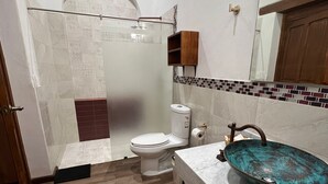 A bathroom with a shower, toilet, and a sink with a decorative basin. - Cozy suite in downtown Morelia (Morelia)