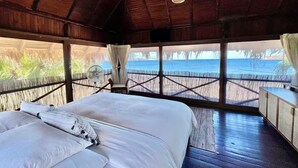 Ein Zimmer mit einem Bett, einem Ventilator und Blick auf das Meer.