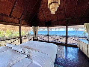 Ein Zimmer mit einem Bett, einem Ventilator und Blick auf das Meer.
