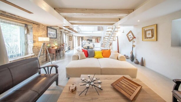 A spacious living room with a sofa, a wooden coffee table, and a staircase leading to an upper level. - Grande longère entre campagne et océan (Guidel)