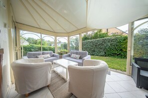 Ein Wintergarten mit einer Sofagarnitur, einem Couchtisch und Blick auf den Garten.