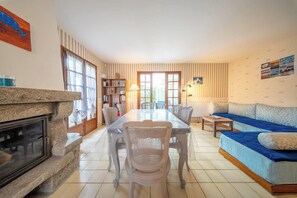 Ein Wohnzimmer mit Esstisch, Sofa, Kamin und Bücherregalen.