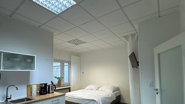 Una camera d'albergo moderna con angolo cottura, un letto, una TV e un bagno.