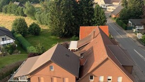 Un edificio a due piani con tetto spiovente, un garage visibile e un vialetto lastricato.