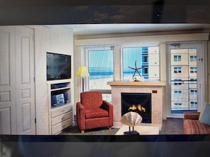Ein Wohnzimmer mit Fernseher, Kamin und Blick auf den Ozean.