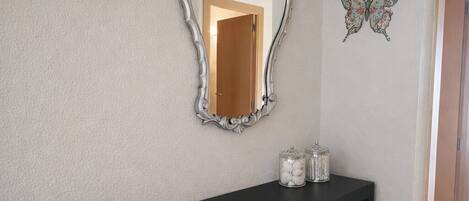 A hallway with a black console table, a decorative mirror, a woven basket, and a butterfly wall art piece.