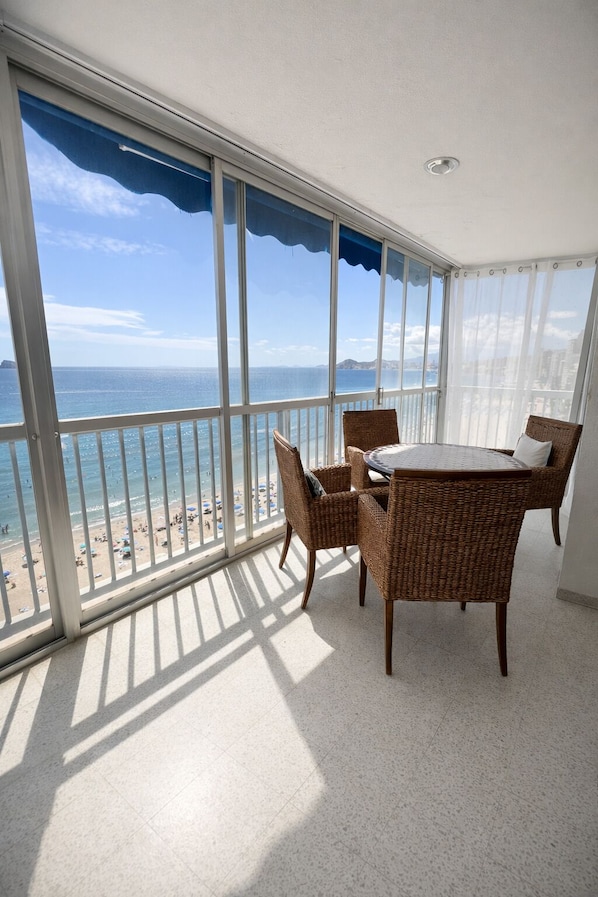 A balcony with a view of the sea and beach, wicker furniture, and a ceiling fan. - Fantastic accommodation in first line of Levante beach, BENIDORM. (Benidorm)
