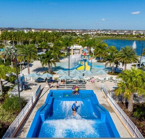 Ein Wasserpark mit großem Pool, Rutschen und Palmen.