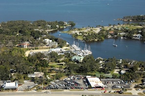 An aerial view of a coastal area with a marina, parked cars, and buildings.