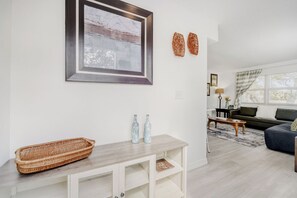 A living room with a sofa, a coffee table, a wicker basket, and two bottles on a table.