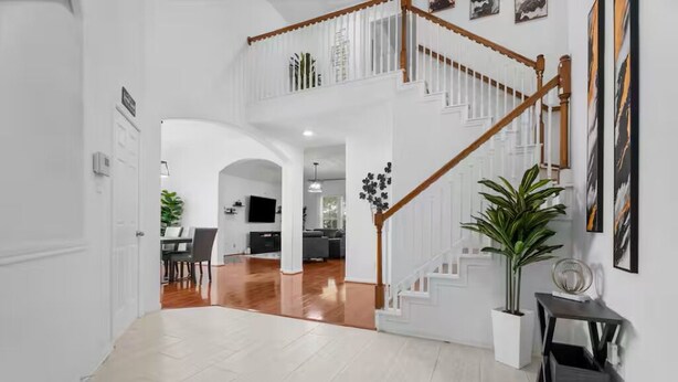 Un pasillo amplio con una escalera que conduce a un segundo piso, un comedor y una cocina visible al fondo.