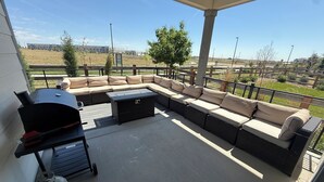 A covered patio with a sectional sofa, a grill, and a gas tank. - Single Story Ranch l New Build l RMNP l 3bd 2bath l Game room (Loveland)