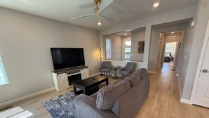 A modern living room with a flat-screen TV, a sofa, a coffee table, and a fireplace. - Single Story Ranch l New Build l RMNP l 3bd 2bath l Game room (Loveland)