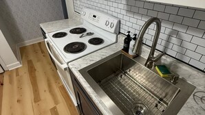 A kitchen with a white stove, stainless steel sink, and wooden flooring. - West Midtown Bungalow Pup Friendly (Atlanta)