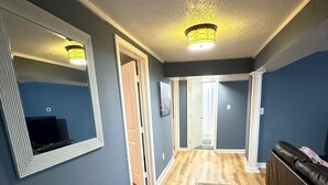 A hallway with a patterned rug, a mirror, a television, and a couch. - West Midtown Bungalow Pup Friendly (Atlanta)
