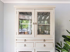 A white cabinet with glass doors, drawers, and metal handles.