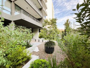 A modern building with multiple balconies, a gravel pathway, and various green plants. - HOM I Las Condes l Parking l Wifi l Piscina l Gym (Las Condes)