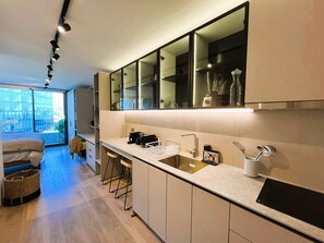 A modern kitchen with a large island, bar stools, a built-in oven, and a large window overlooking a balcony. - HOM I Las Condes l Parking l Wifi l Piscina l Gym (Las Condes)