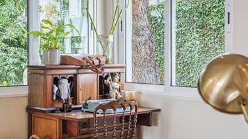A wooden desk with a lamp, a vase with plants, and a small statue.