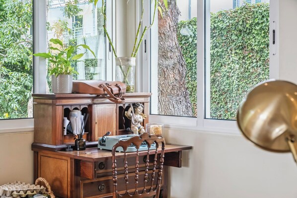 Et træskrivebord med en lampe, en vase med planter og en lille statue.