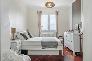 Un dormitorio con cama, cómoda y ventana con cortinas.