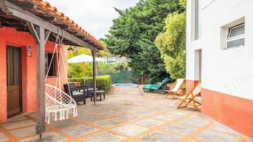 A patio area with a hanging chair, lounge chairs, and a hot tub.